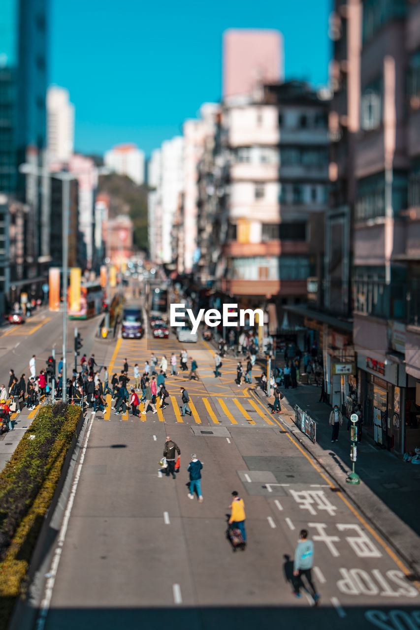 city, architecture, building exterior, transportation, street, road, built structure, city life, crowd, urban area, city street, lane, mode of transportation, group of people, metropolitan area, car, large group of people, downtown, motor vehicle, cityscape, road marking, sky, infrastructure, sign, building, travel destinations, day, traffic, travel, nature, outdoors, high angle view, marking, symbol, motion, skyscraper, crossing, crossroad, walking, on the move, office building exterior, crosswalk, metropolis, zebra crossing, neighbourhood, residential district, clear sky
