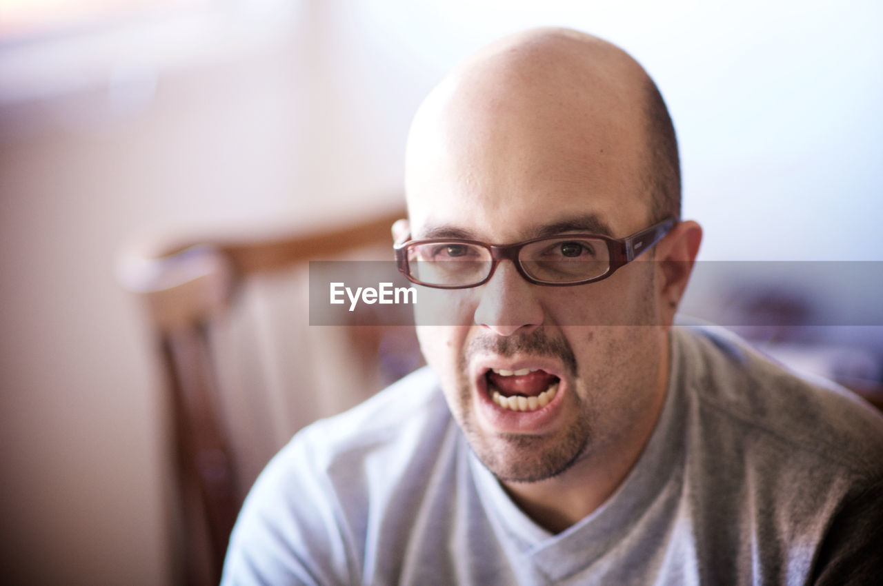 Portrait of man in eyeglasses making face at home