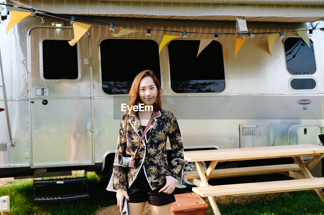 Portrait of young woman standing by motor home