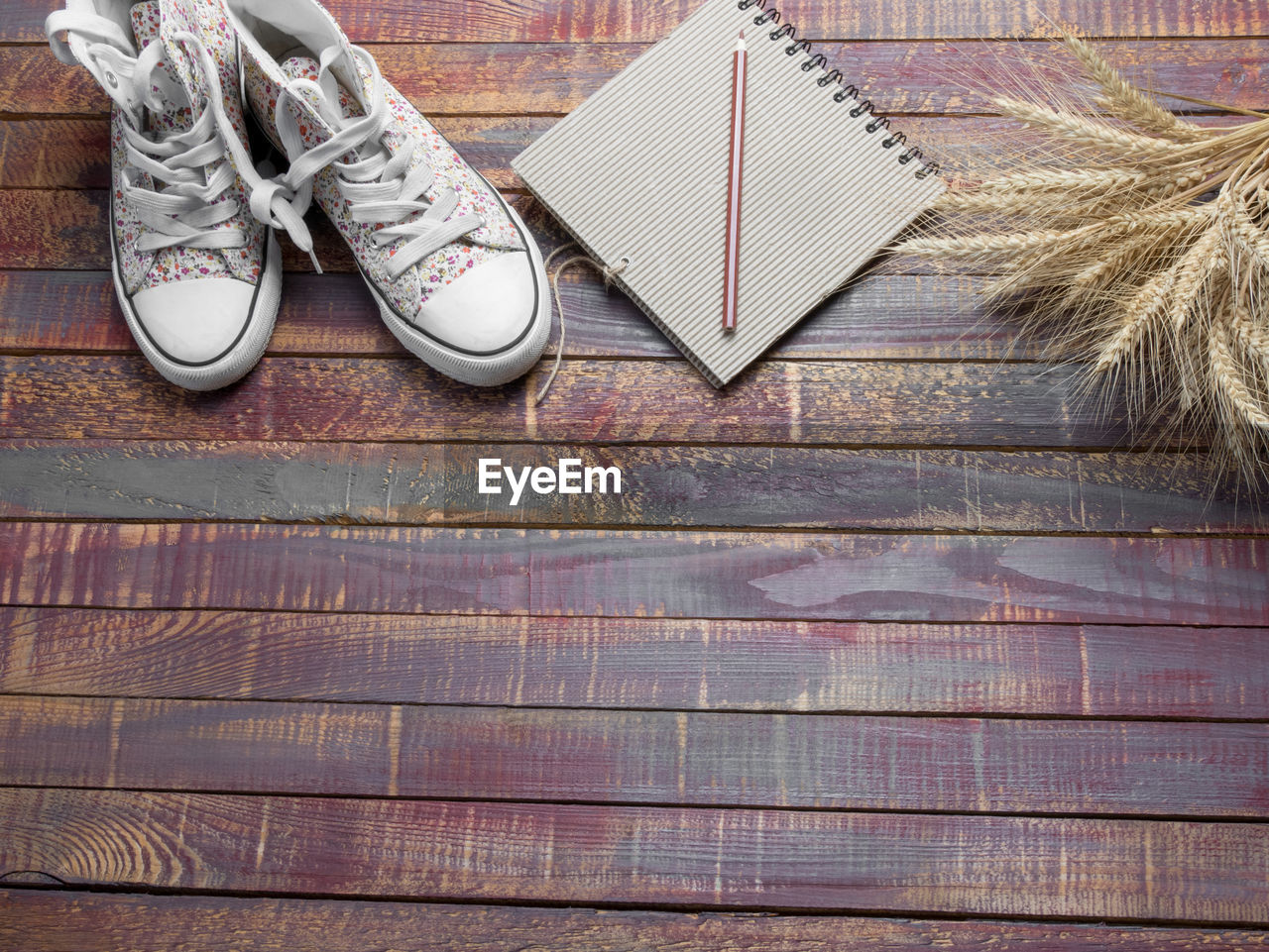 Close-up of shoes and spiral notebook with cereal plants on wooden table