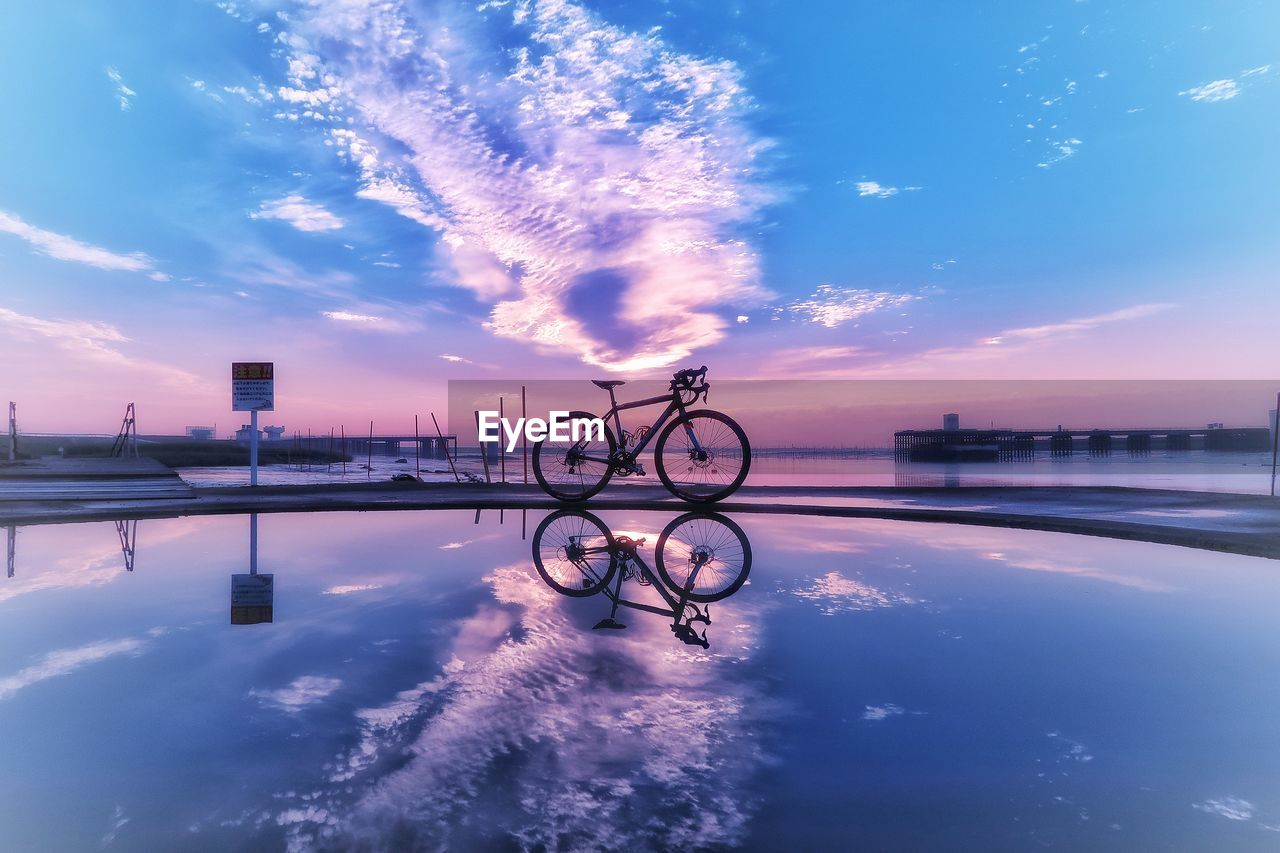 Bicycles on lake against blue sky