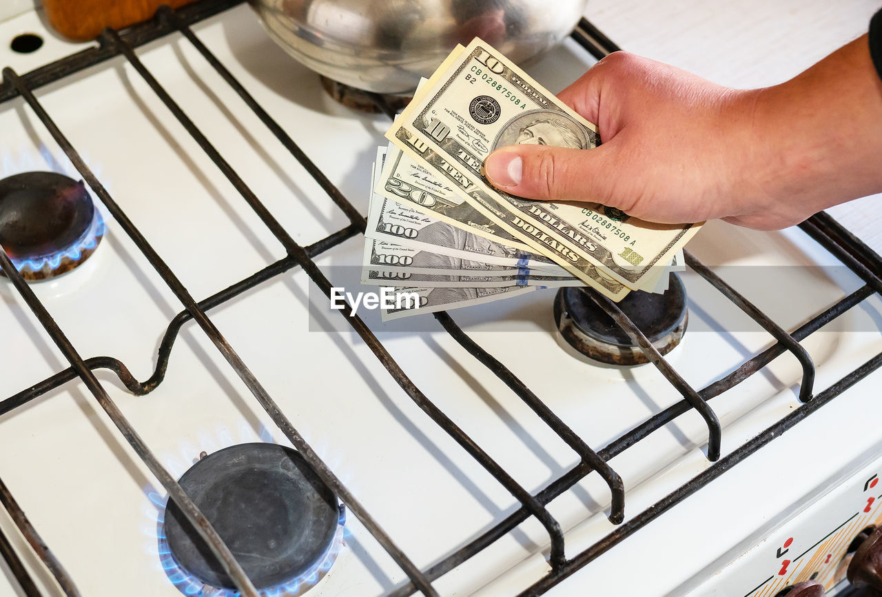 Payment of utility services. dollar bills are held in their hands near a burning gas burner. 