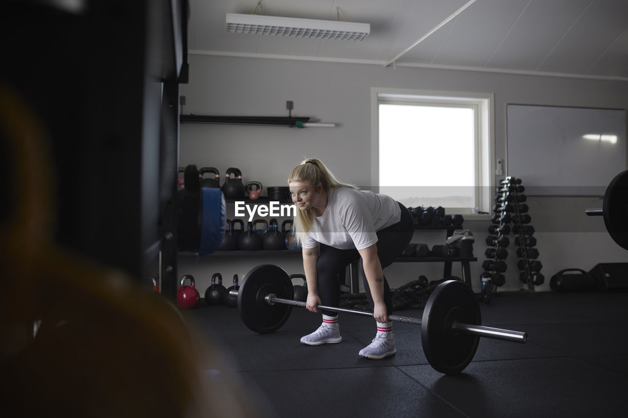 Mid adult woman lifting barbell in gym