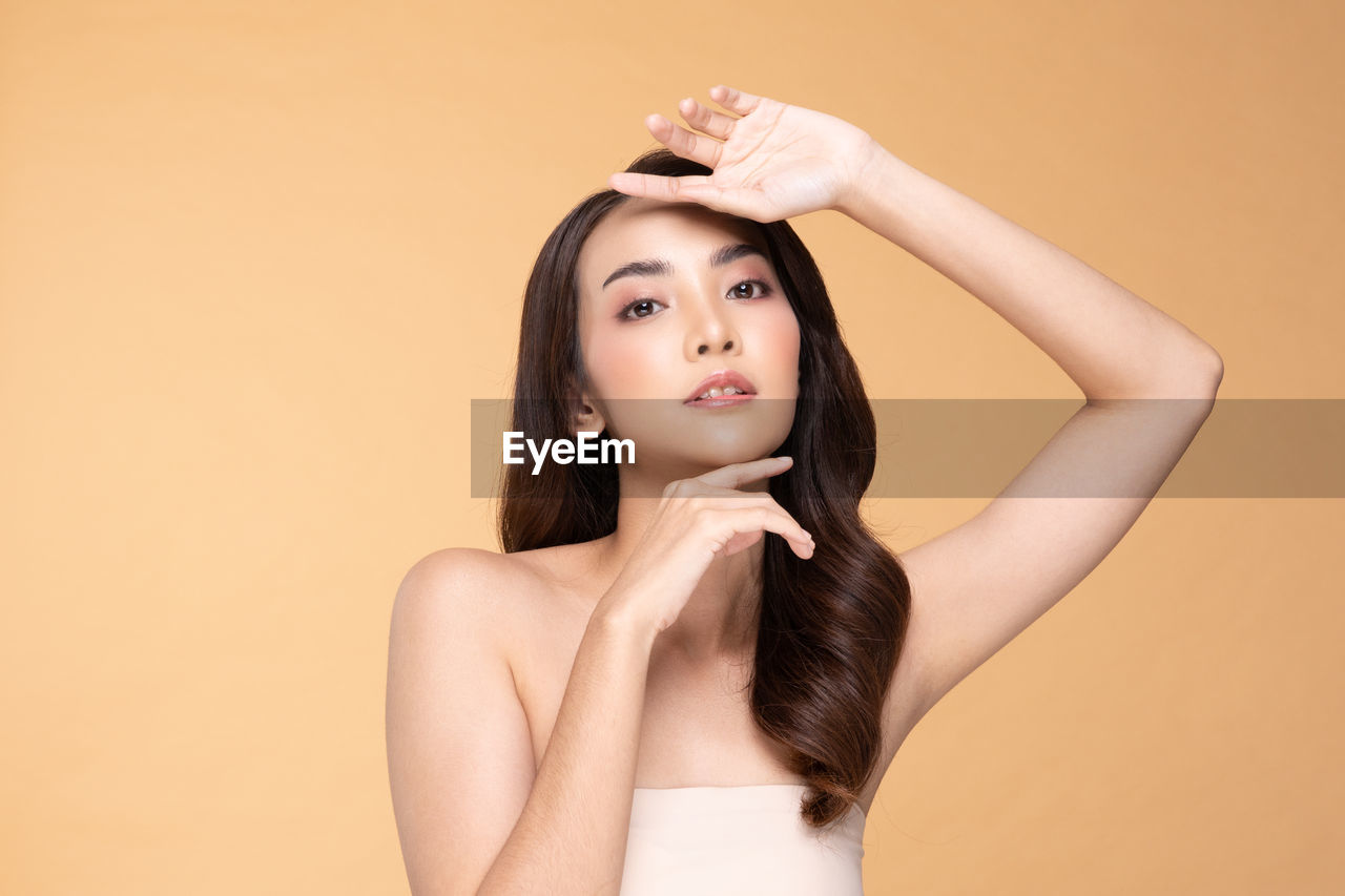 PORTRAIT OF A BEAUTIFUL YOUNG WOMAN OVER GRAY BACKGROUND