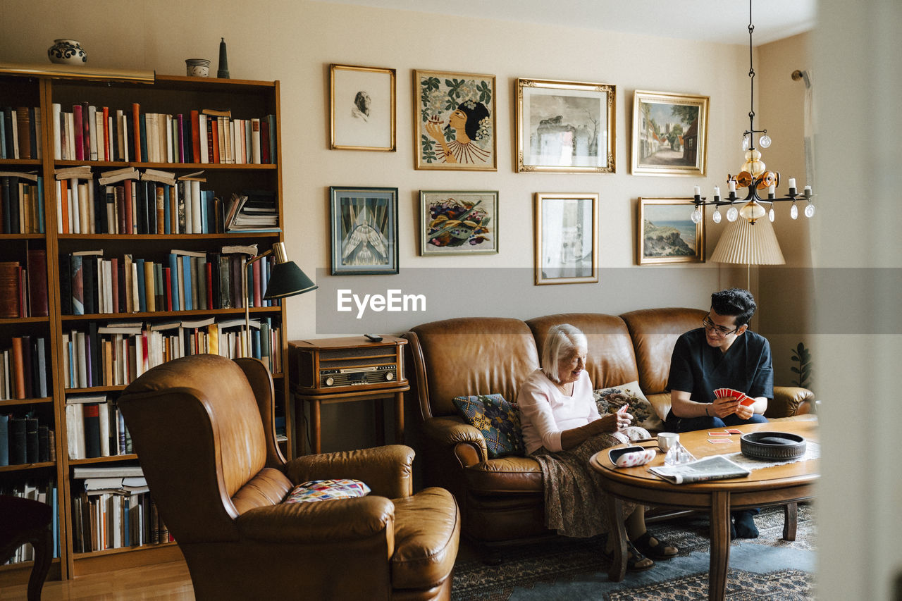 Young male nurse spending leisure time while playing cards at home