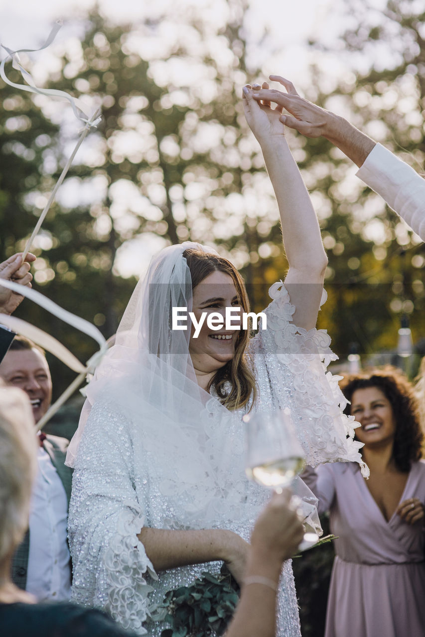 Happy newlywed couple dancing amidst family and friends at wedding