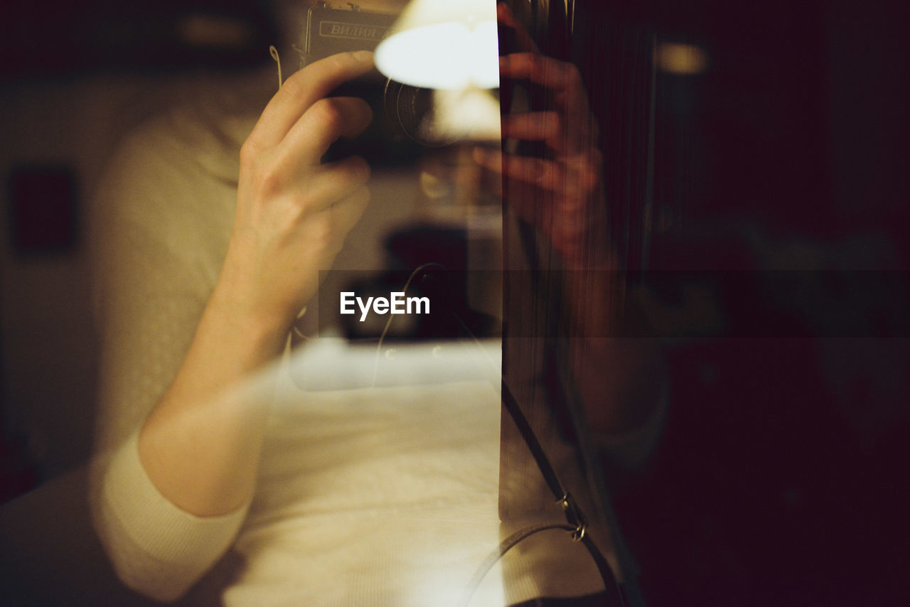 Double exposure of illuminated lamp and woman holding vintage camera