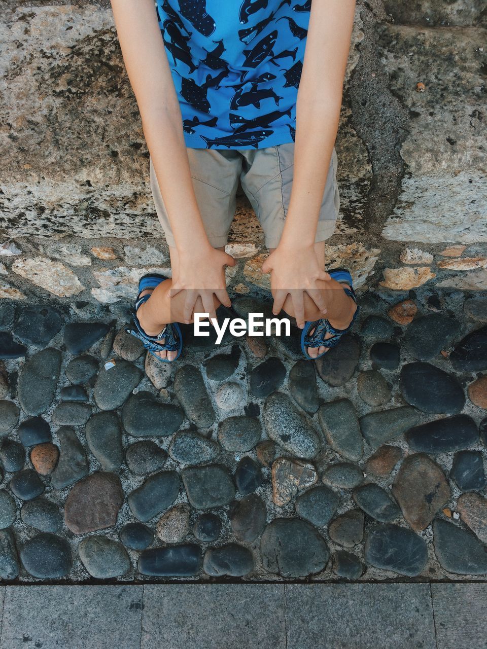 Low section of child sitting on stone wall