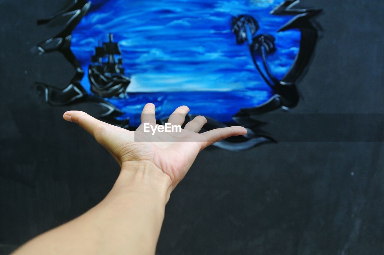 Cropped image of hand gesturing towards graffiti wall