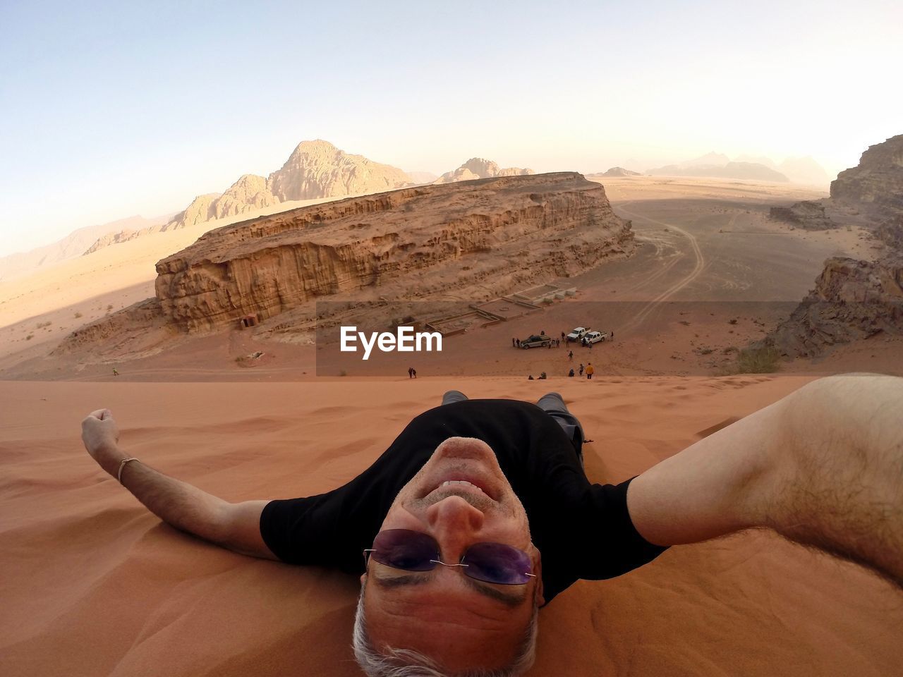 Man lying at desert against clear sky