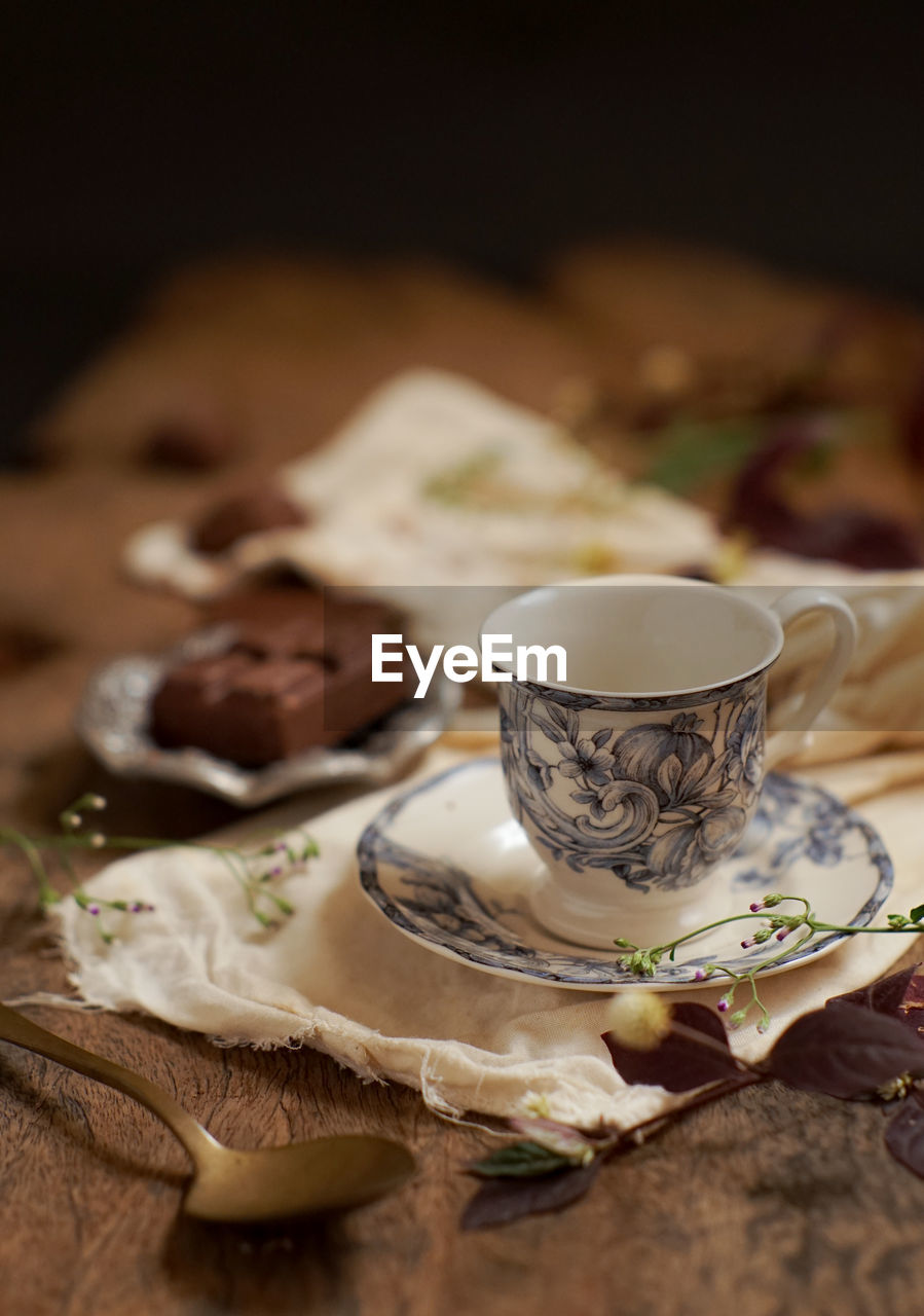 CLOSE-UP OF COFFEE CUP ON TABLE AGAINST BLACK BACKGROUND