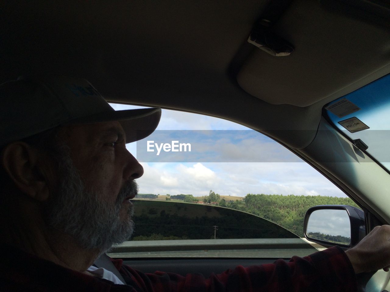 Side view of senior man driving car by field