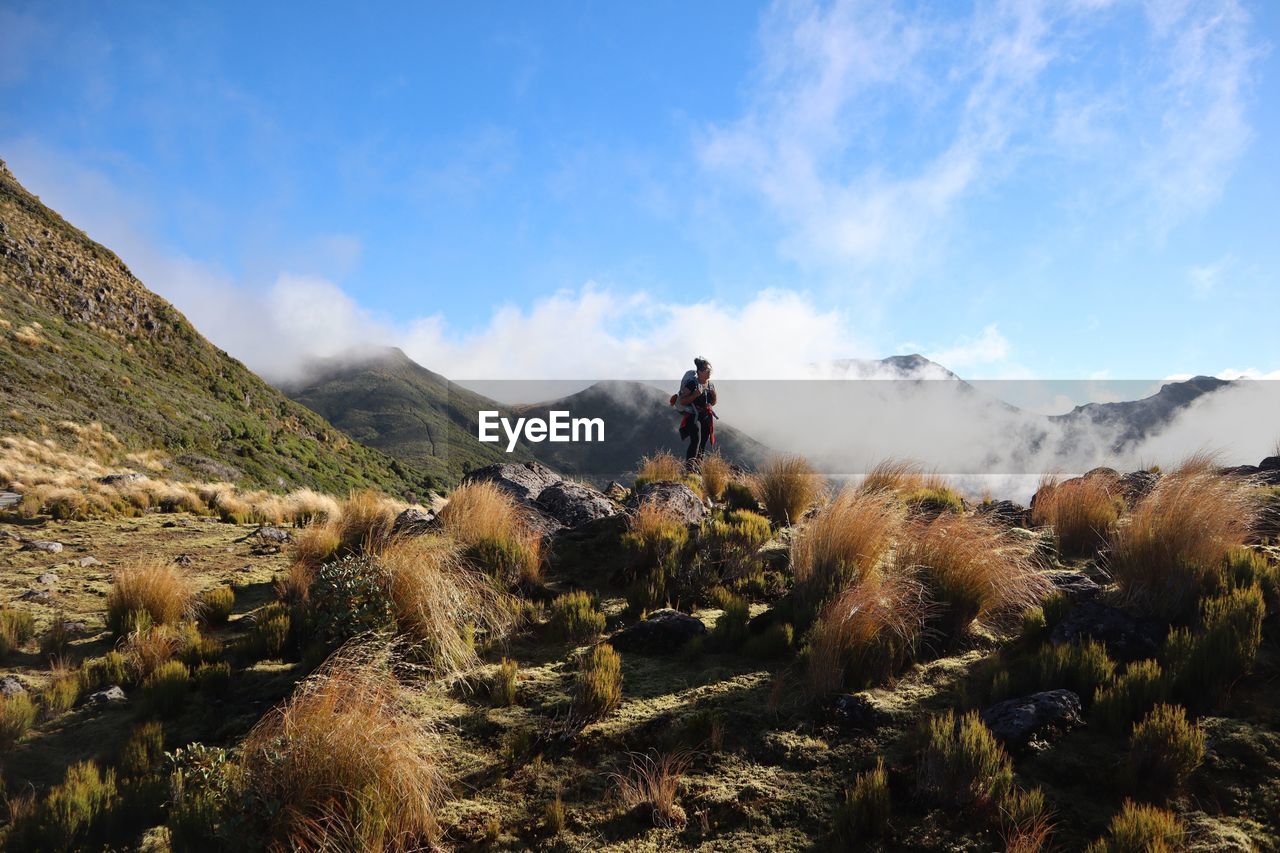 Full length of woman standing on mountain against sky