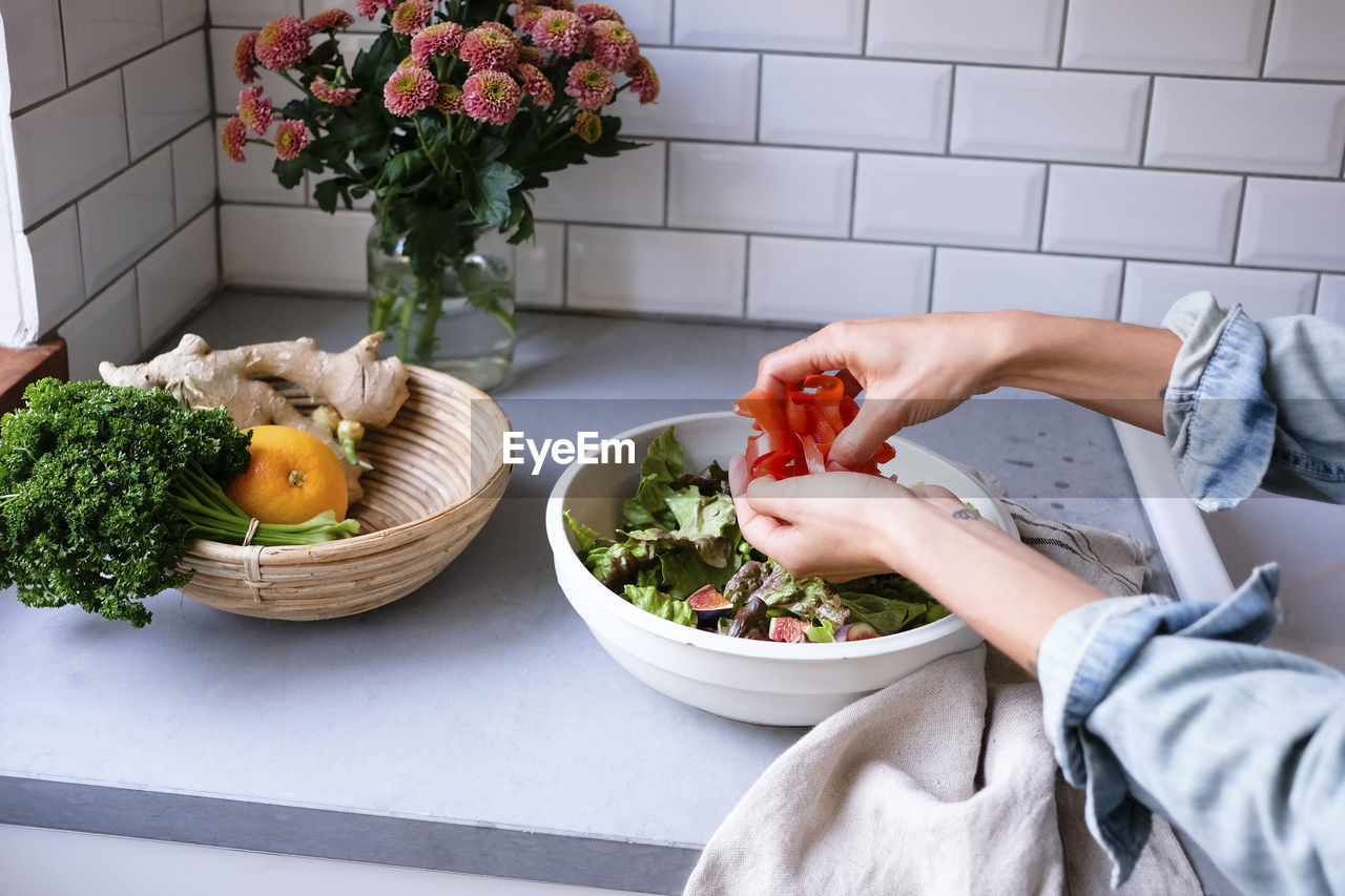 Cropped image of woman making salad at kitchen counter