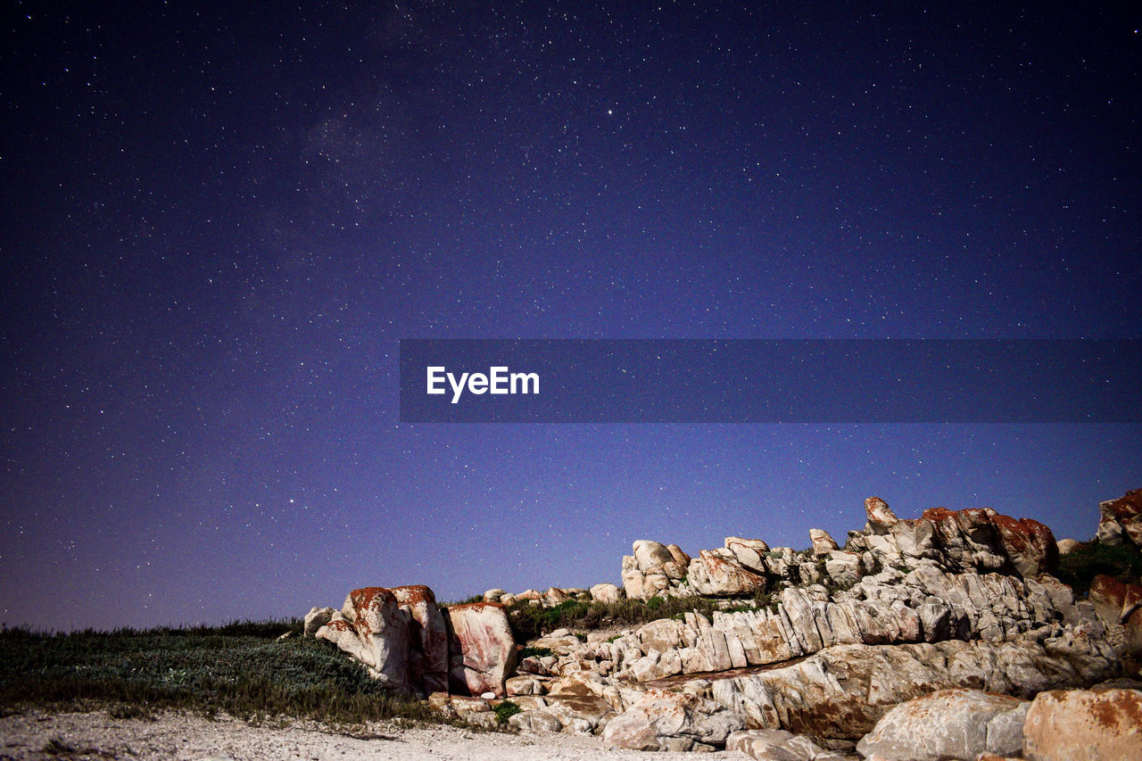 SCENIC VIEW OF ROCKS ON FIELD AGAINST SKY