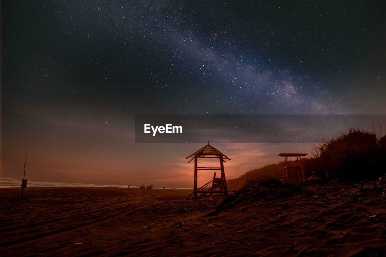 Lifeguard hut on beach against sky at night