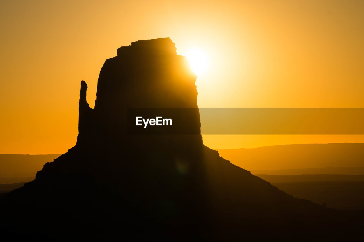 SCENIC VIEW OF SILHOUETTE ROCK FORMATION AGAINST ORANGE SKY