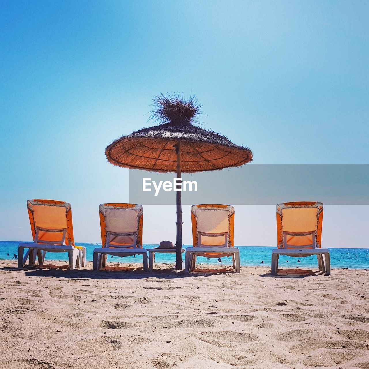 DECK CHAIRS ON BEACH AGAINST CLEAR BLUE SKY