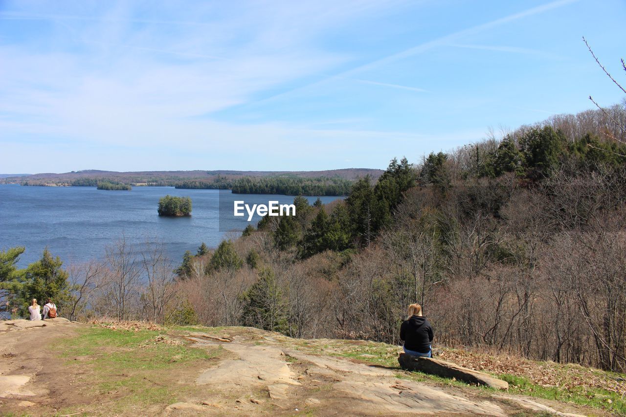 Mid distance view of man sitting on rock against sky