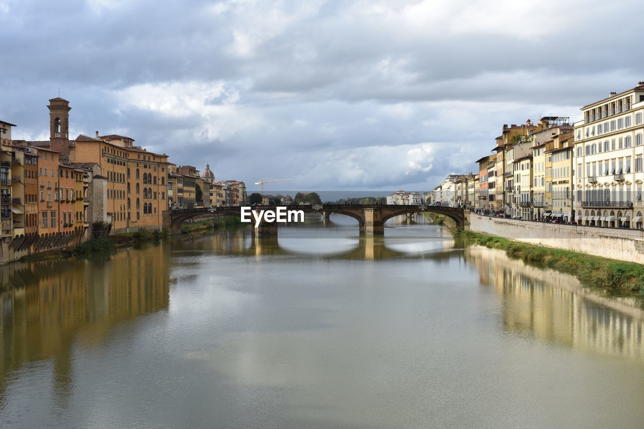 BRIDGE OVER RIVER AMIDST BUILDINGS AGAINST SKY