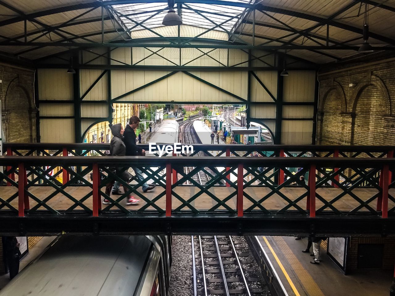 Man and woman walking on footbridge at railroad station