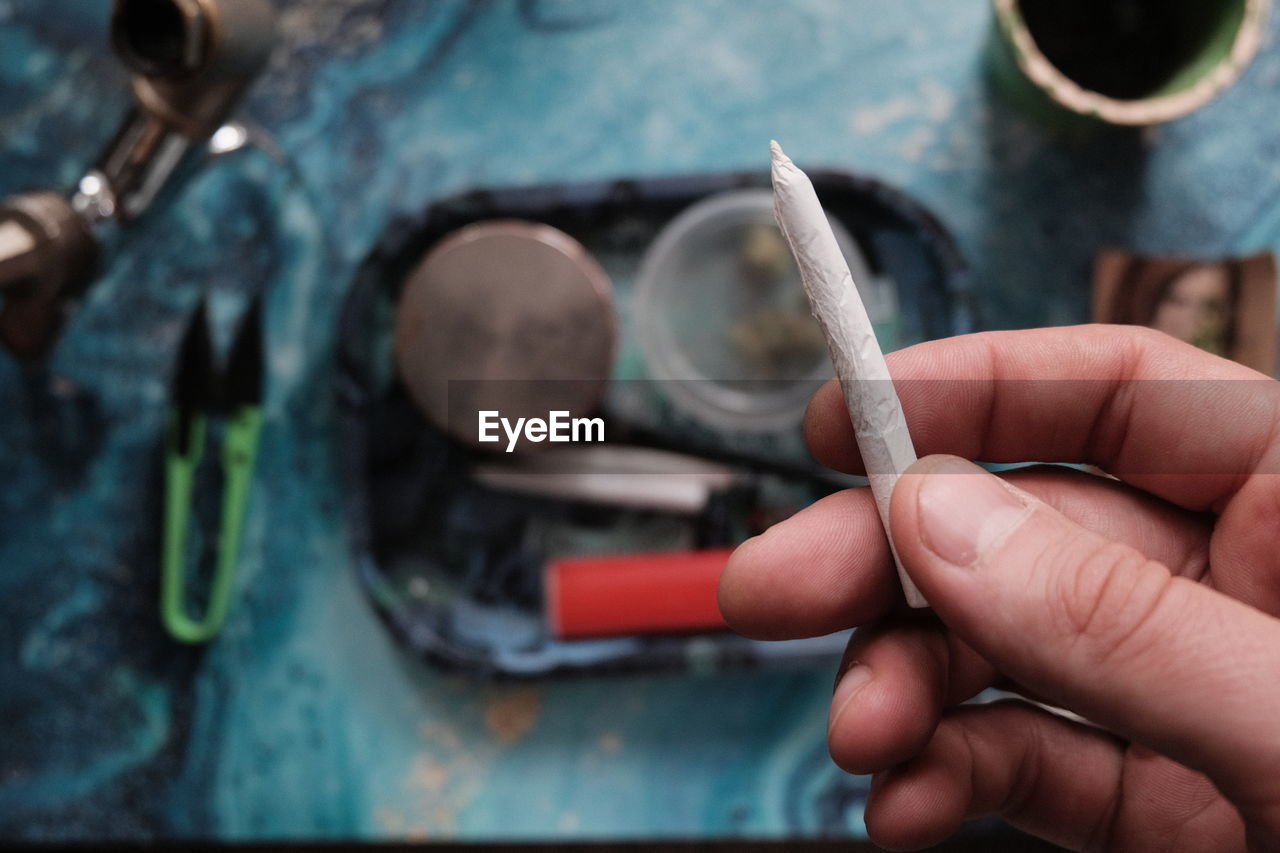 close-up of hand holding cigarette on table