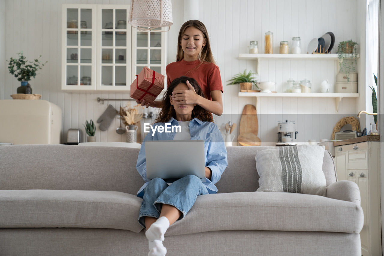 rear view of woman using laptop while sitting on sofa at home