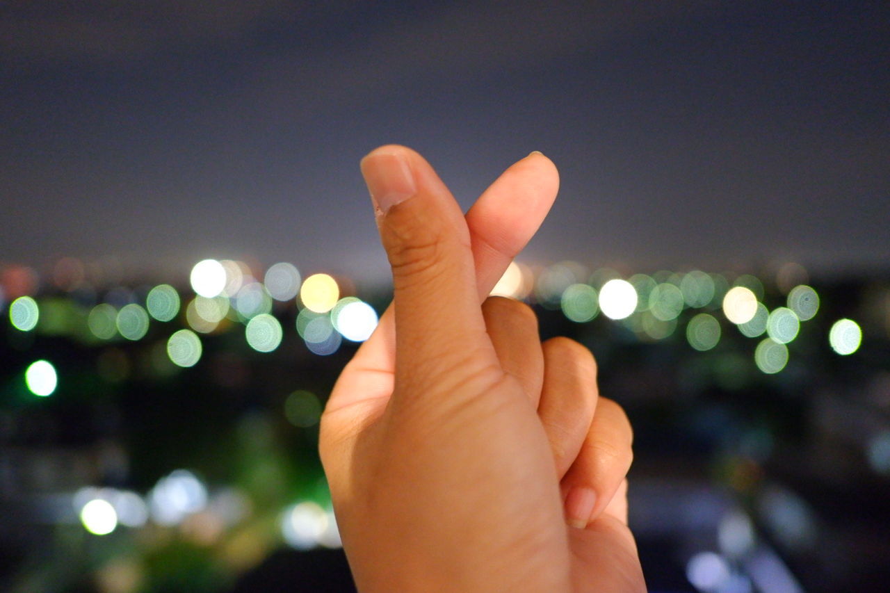 Cropped image of hand against sky at night