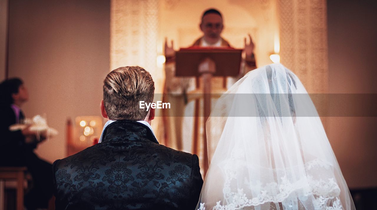 Rear view of bride and bridegroom standing at altar during wedding ceremony