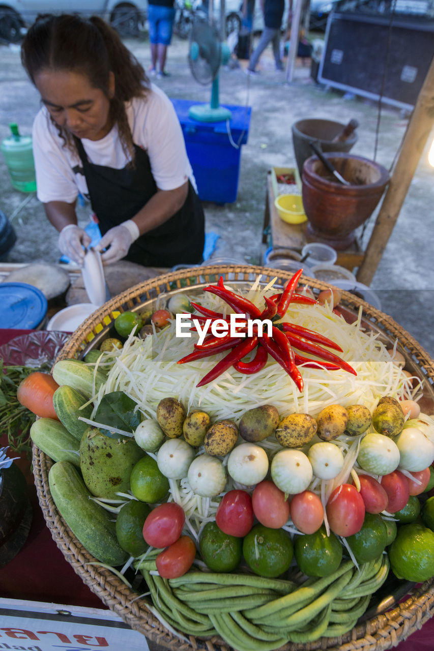 HIGH ANGLE VIEW OF WOMAN HOLDING FRUITS IN MARKET