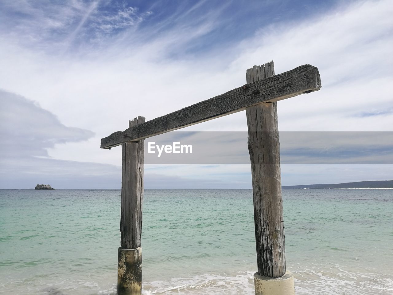 CROSS ON WOODEN POST AT BEACH AGAINST SKY