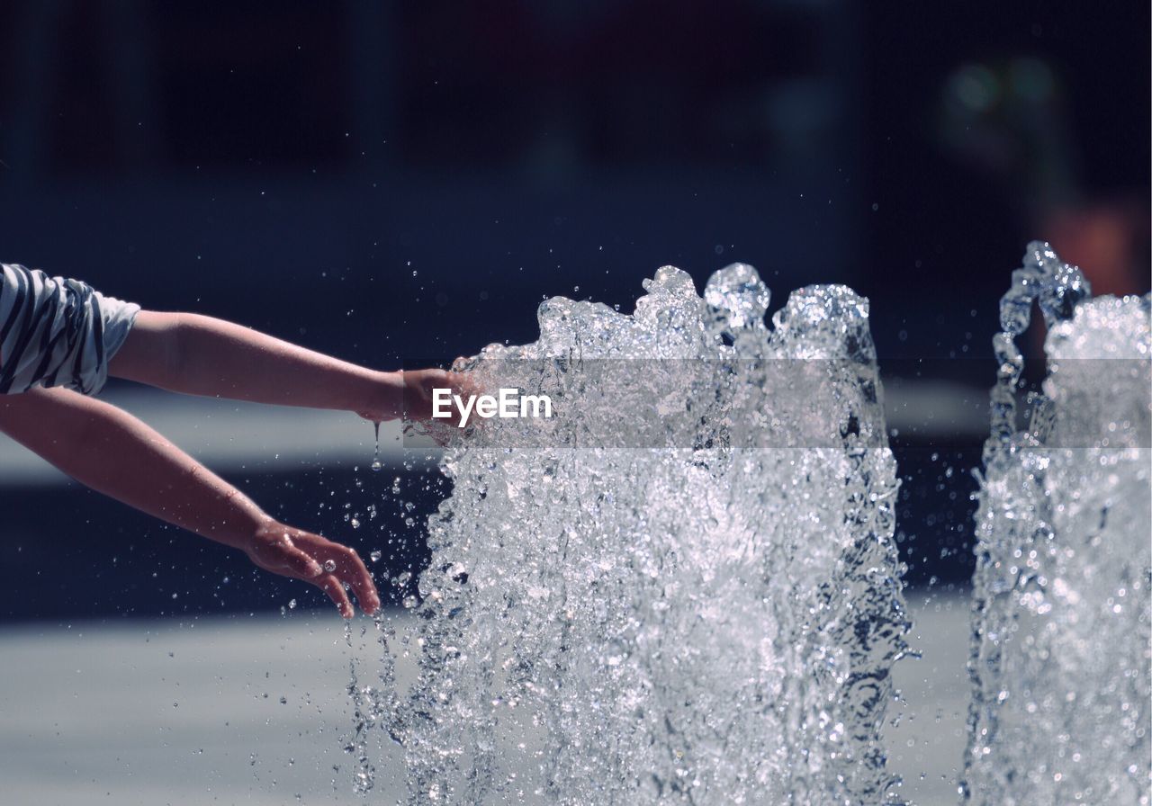 Cropped hands of person touching fountain