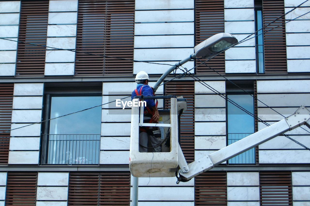 Rear view of worker repairing street light in city