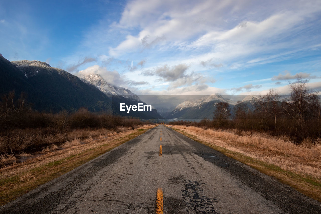 Empty road towards mountains along countryside landscape