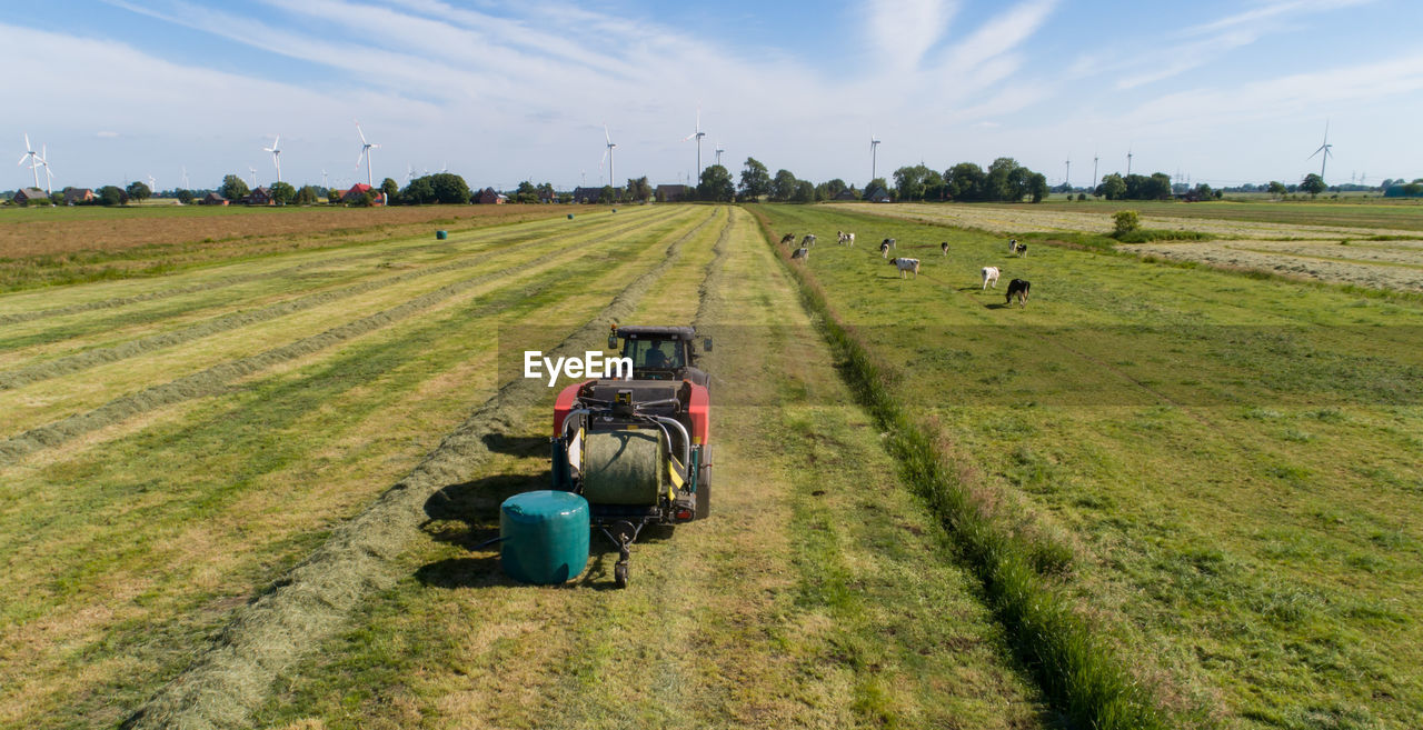 Black tractor with a red straw chamber press during the straw harvest on a mown field