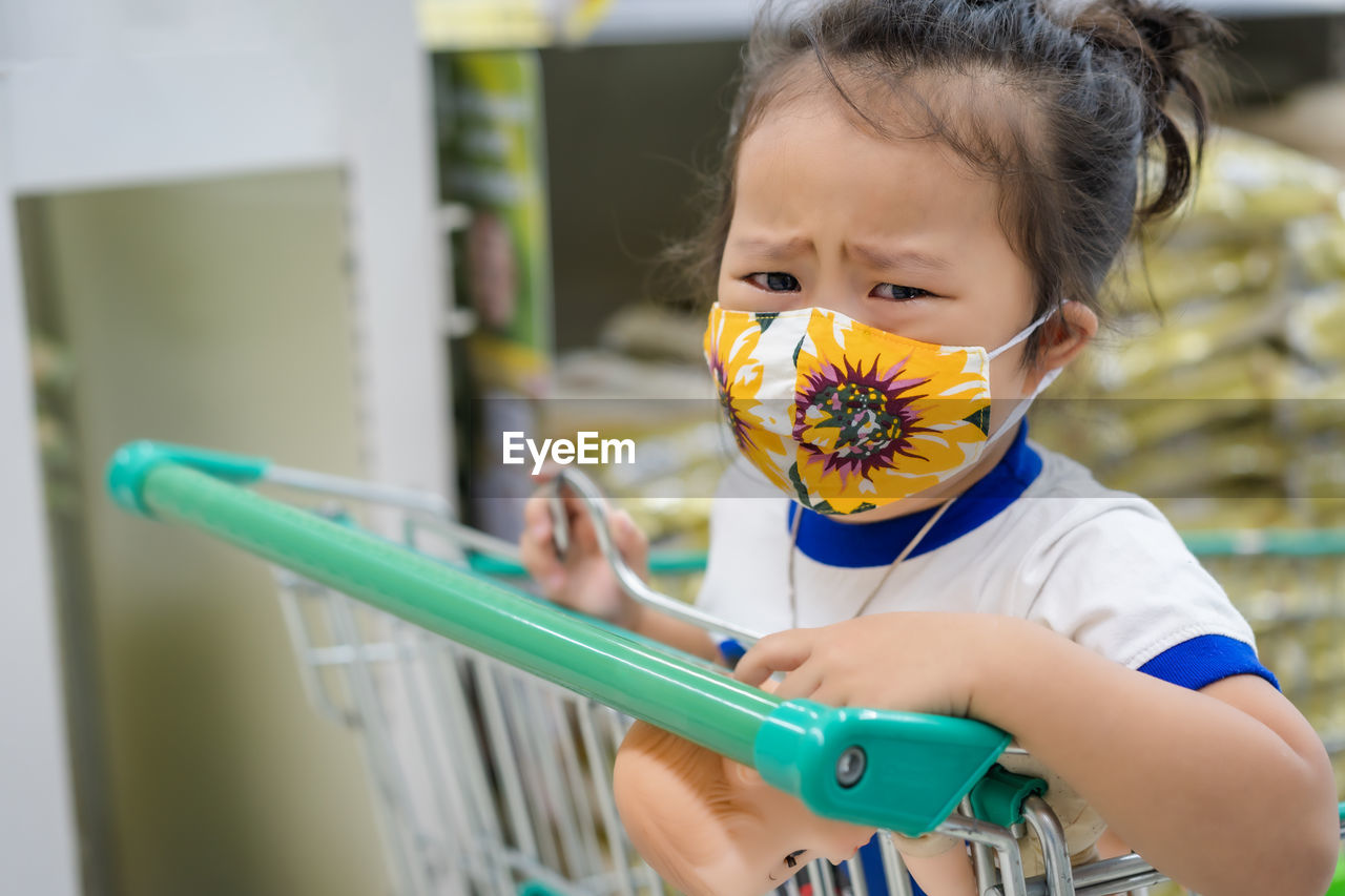 Girl wearing mask crying in supermarket