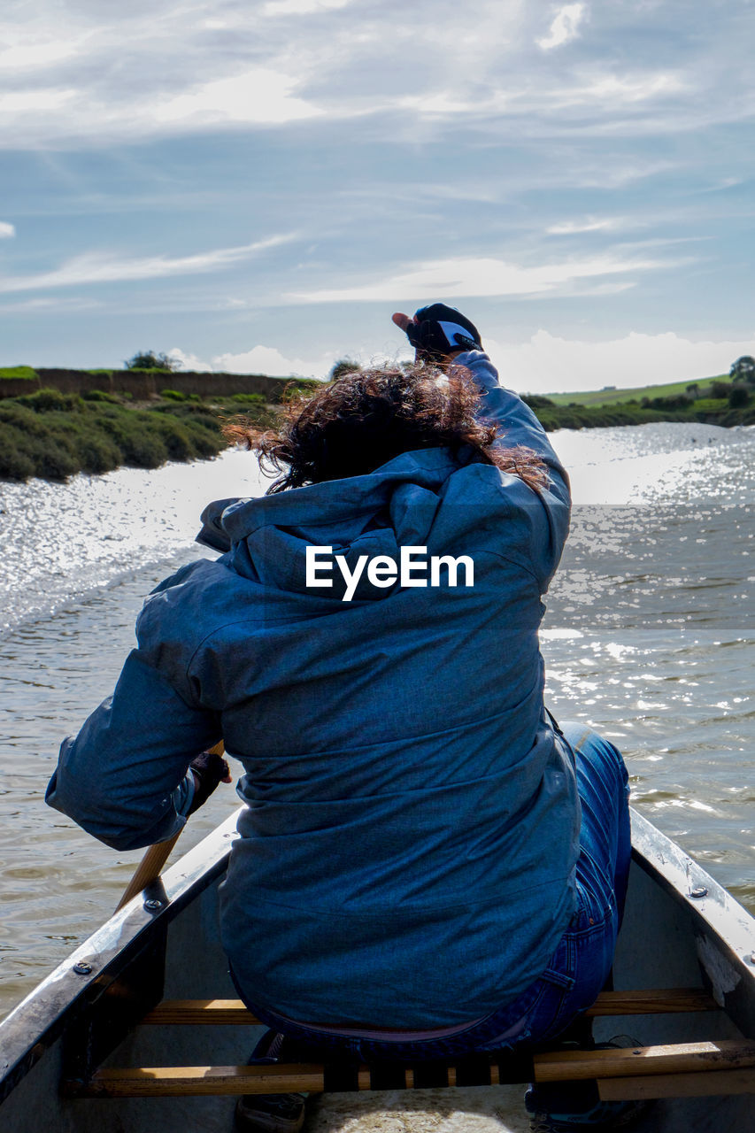 Rear view of woman sitting on boat in lake