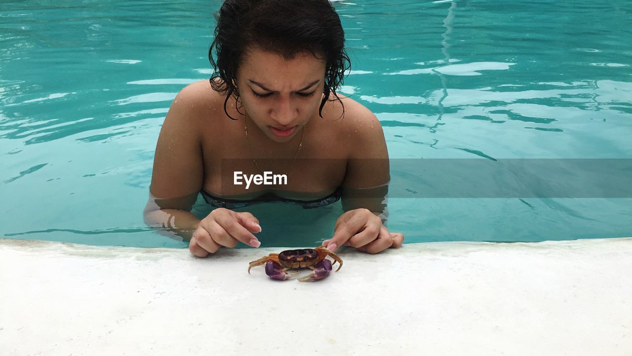 Young woman catching crab while standing in swimming pool