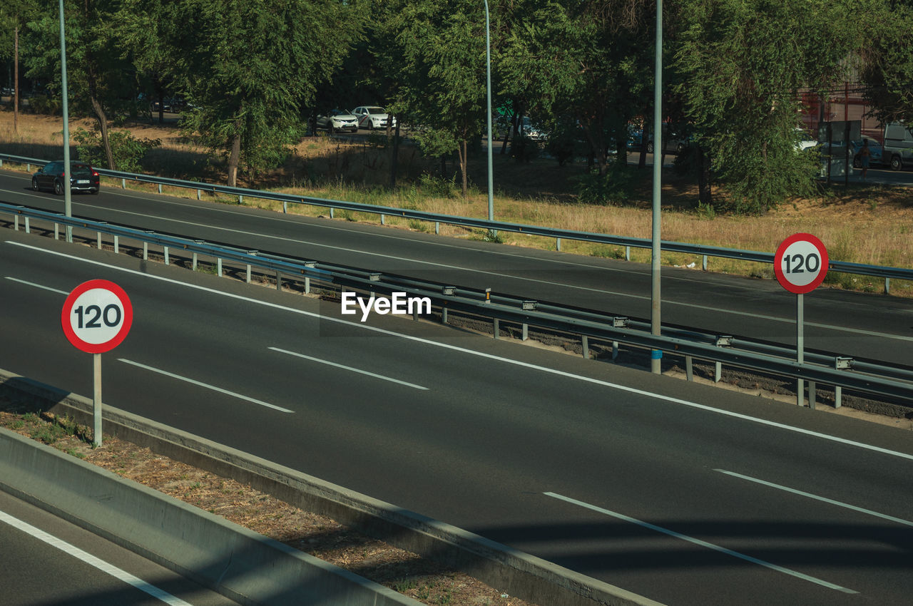 ROAD SIGN BY TREES AGAINST BLURRED MOTION