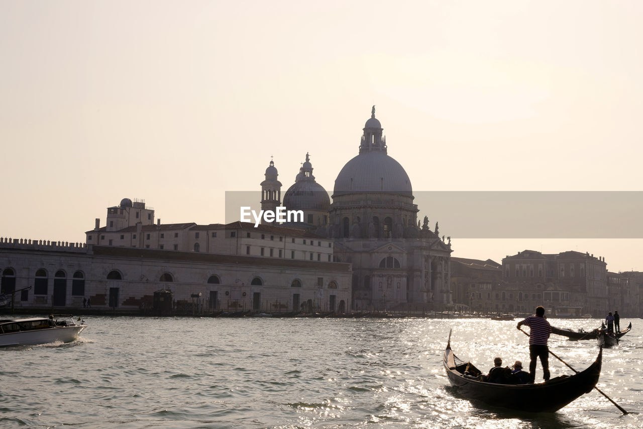 VIEW OF CHURCH AT WATERFRONT AGAINST SUNSET SKY