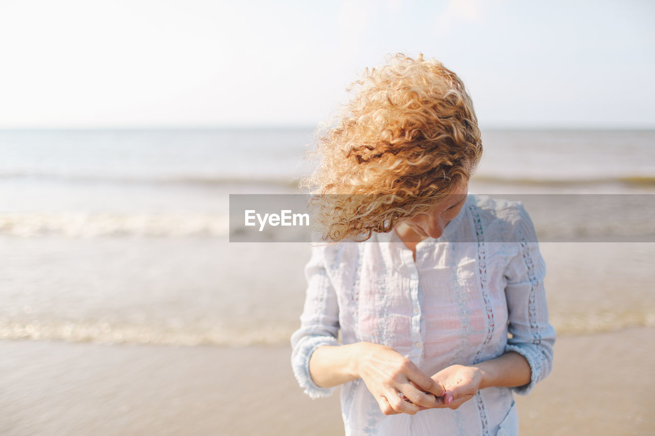 Young woman collecting seashells on beach