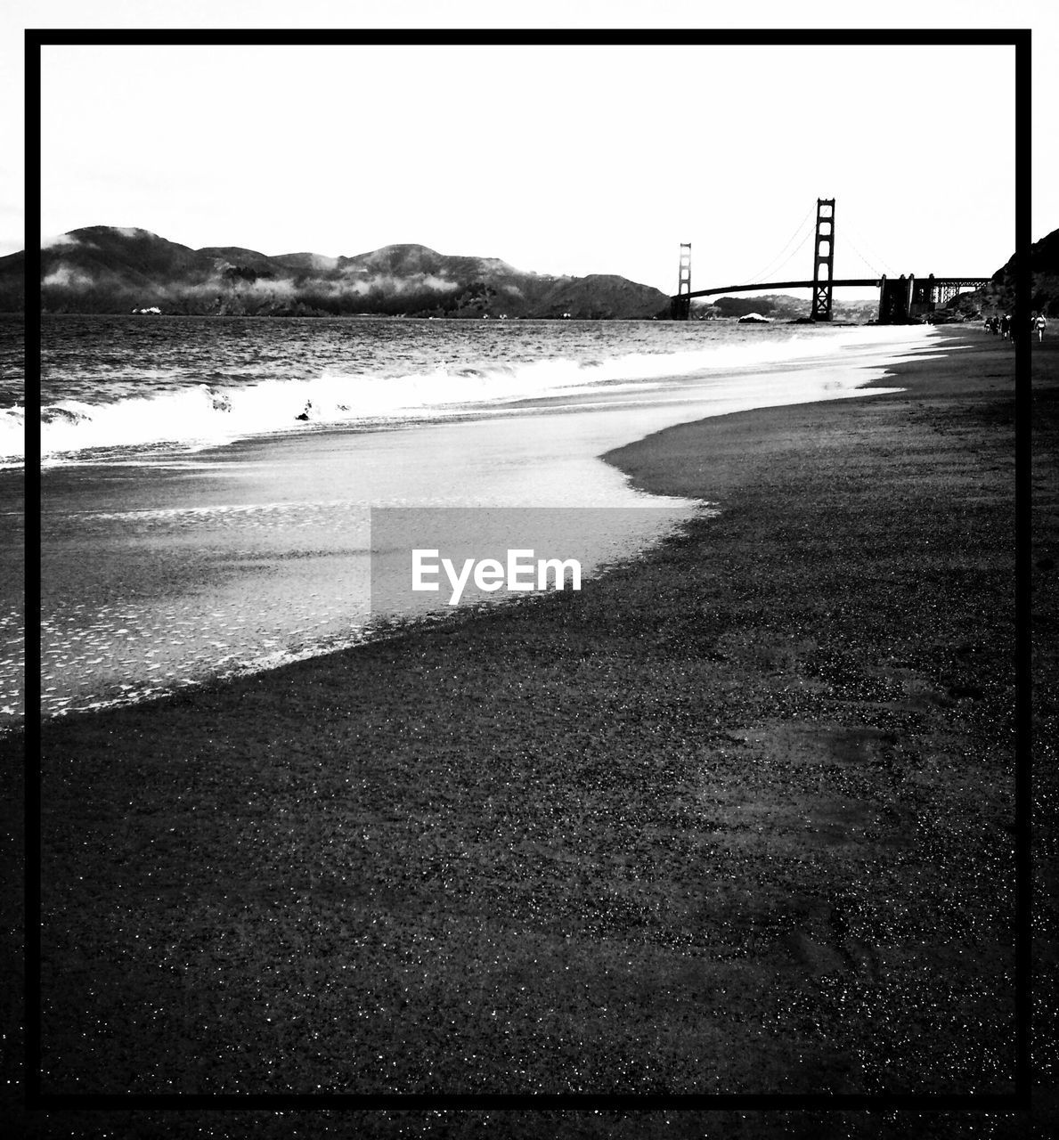 Beach by golden gate bridge against clear sky