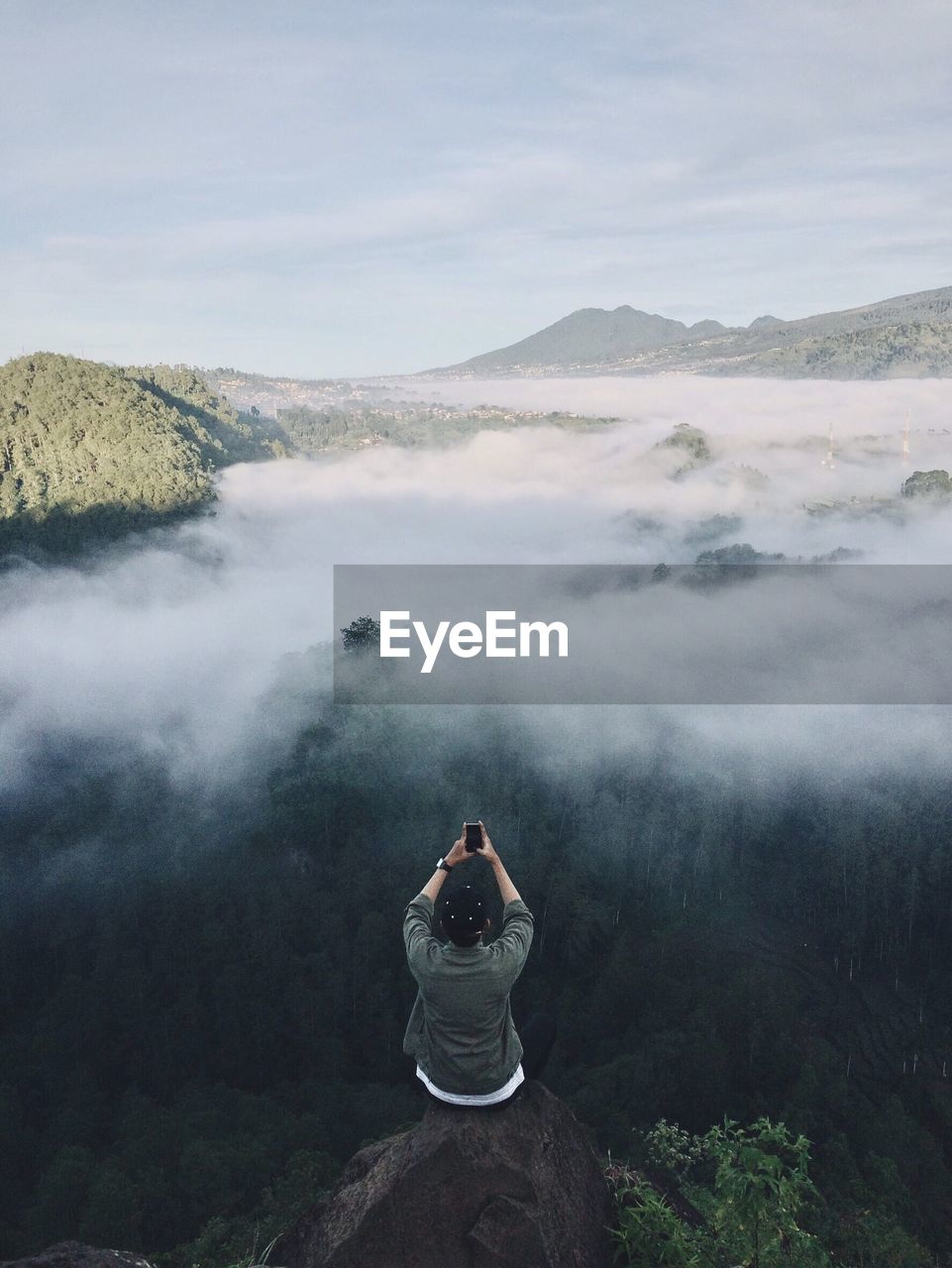 Rear view of man photographing on mountain against sky