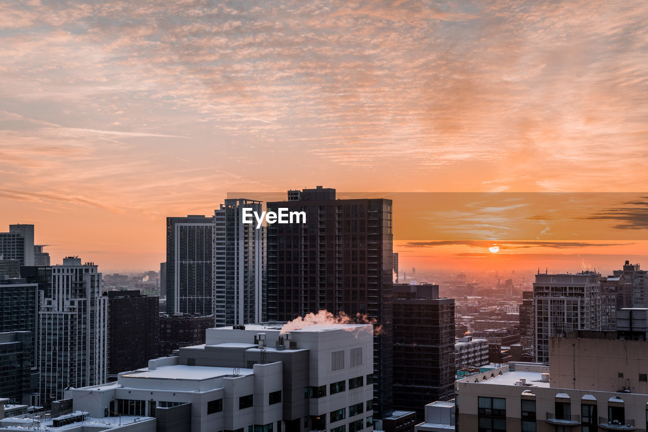 Cityscape against cloudy sky during sunset