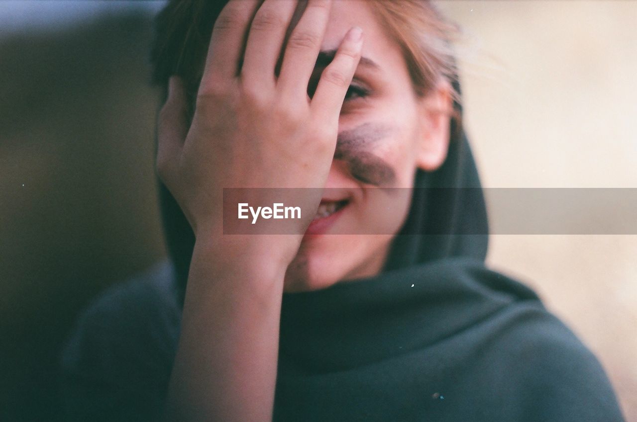 Close-up of woman covering face with hand outdoors