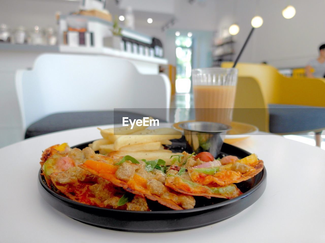 Close-up of pizza and french fries on table at cafe