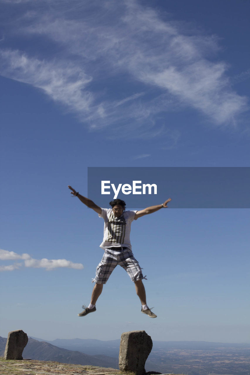 Mid adult man jumping against blue sky