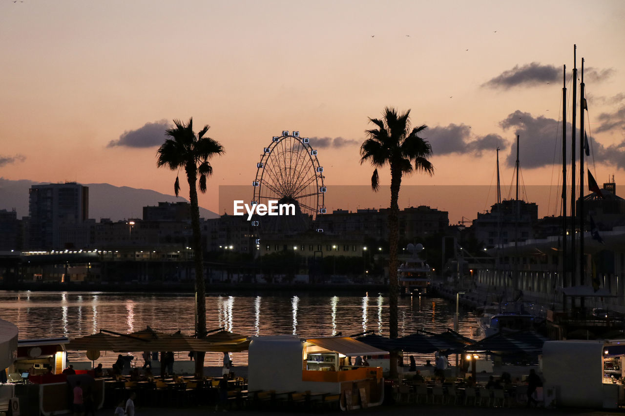 View of ferris wheel in city at sunset