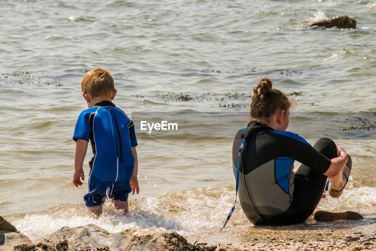 Rear view of children in wetsuit at beach