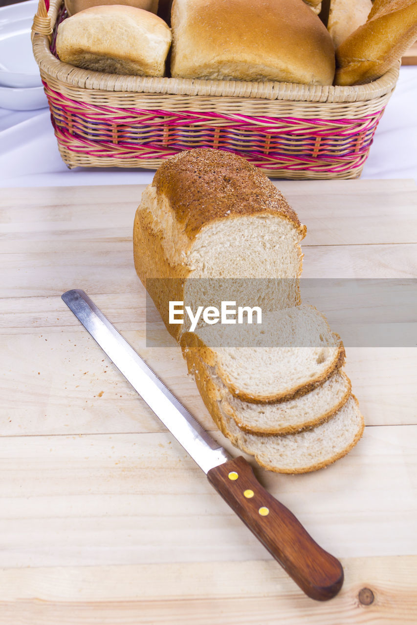 High angle view of fresh sliced breads with knife on table